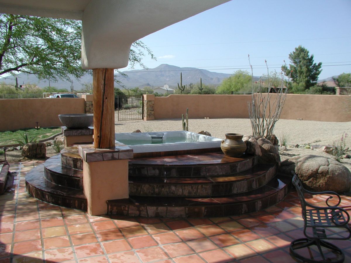 Desert backyard hot tub on curved tiled steps, terracotta patio, mountain view and cacti