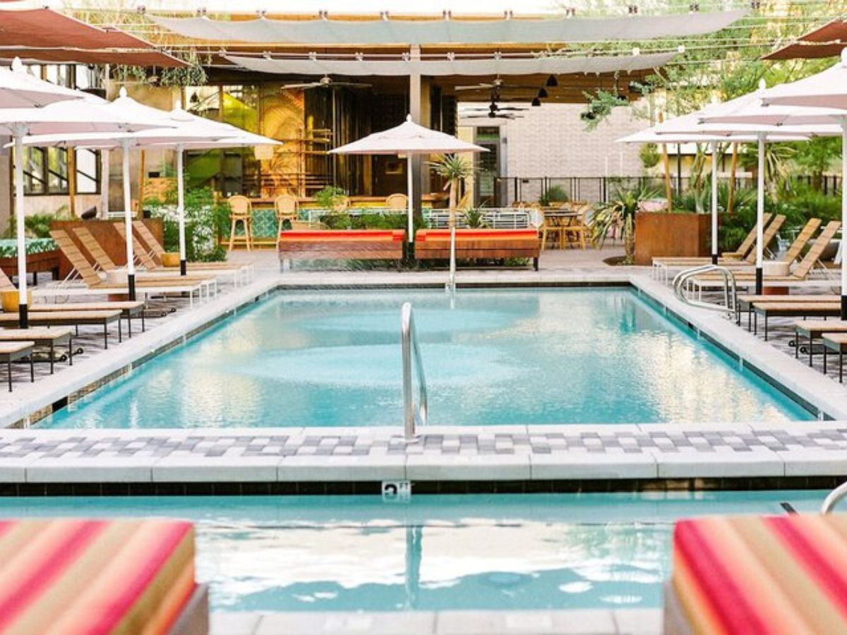 Outdoor hotel pool with sun loungers, umbrellas and modern poolside seating at a boutique resort.
