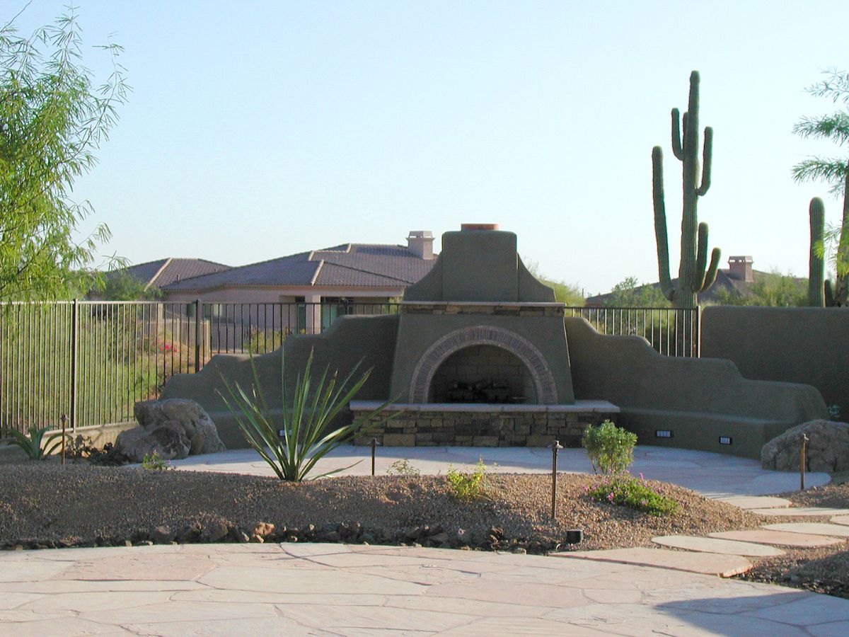 Outdoor fireplace, desert patio: Southwestern kiva-style fireplace with saguaro cacti and stone paving
