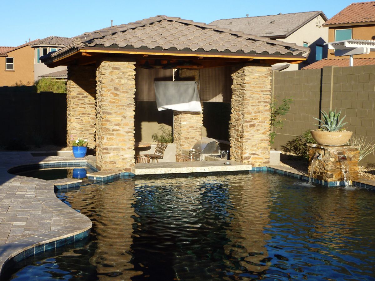 Backyard pool design: luxury swimming pool with stone cabana, outdoor kitchen grill, paver deck and fountain